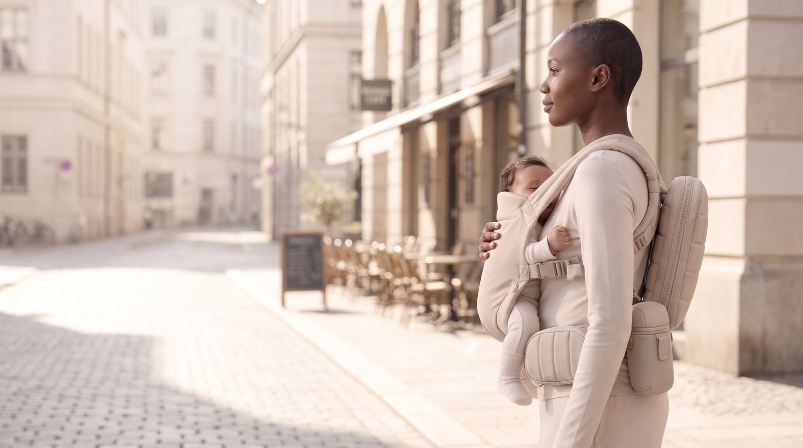 Woman with baby in a carrier and the belt on a sunny city street